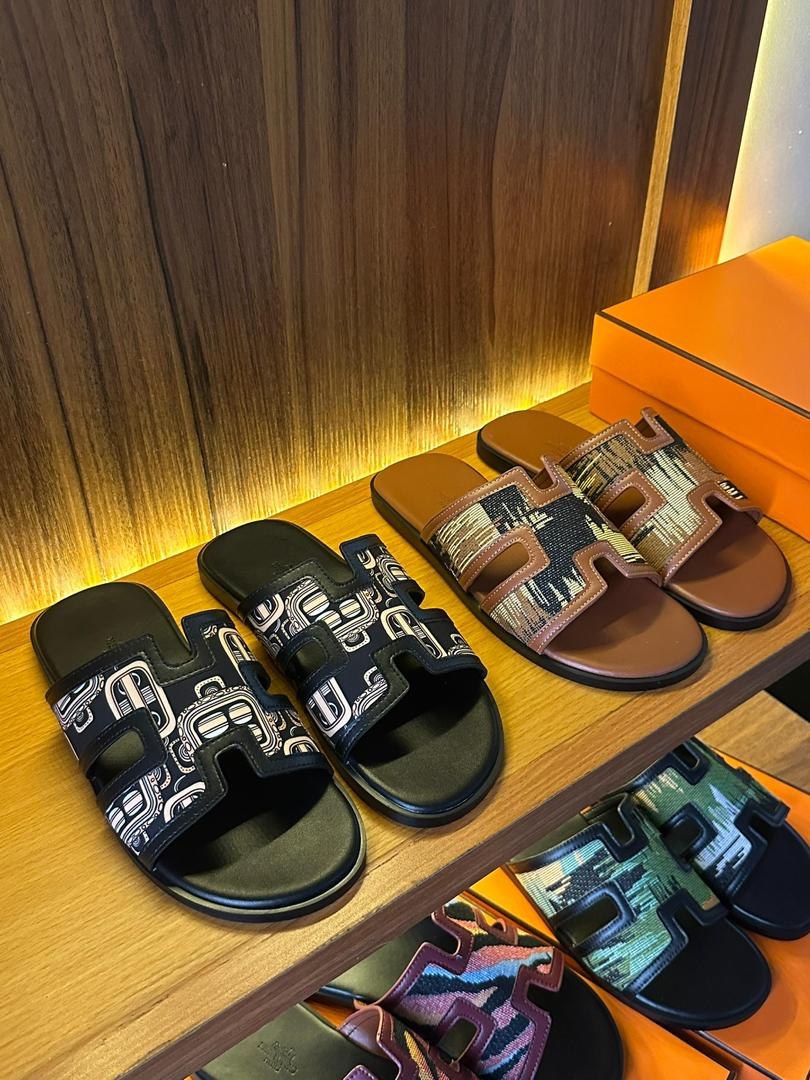 A collection of stylish and comfortable slides for men on a wooden shelf