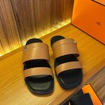 A pair of Hermes sandals placed on a wooden table, showcasing their sleek design and luxurious appeal