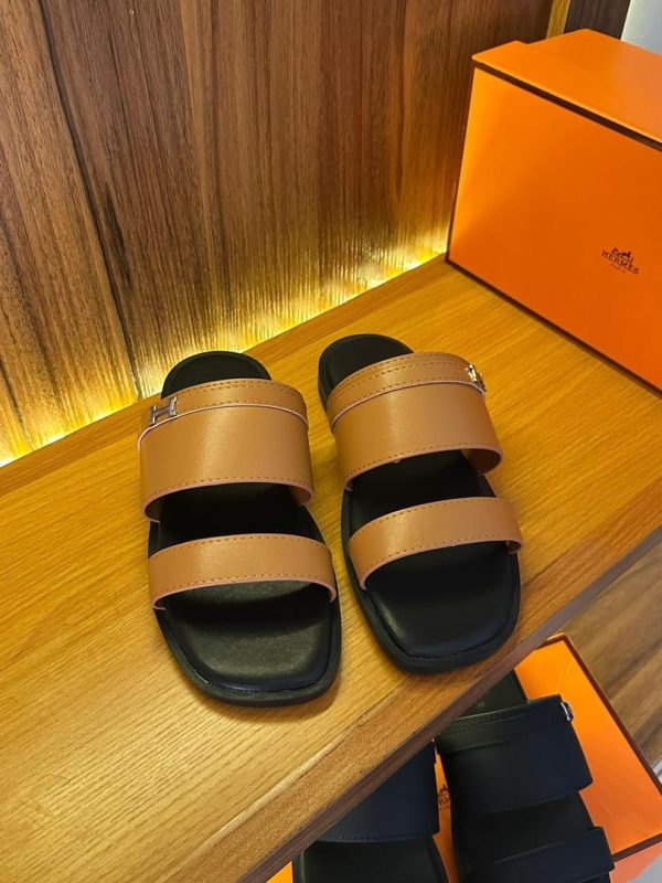 root A pair of Hermes sandals placed on a wooden table, showcasing their sleek design and luxurious appeal