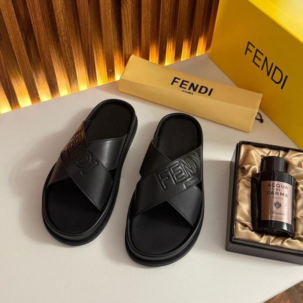 A pair of black Fendi sandals on a white surface, accompanied by a yellow box with the Fendi logo and a bottle of perfume in a box