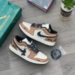 A pair of Air Jordan 1 Low 'Stussy' sneakers on a wooden floor, with a green shoebox and a PlayStation 4 game case in the background.