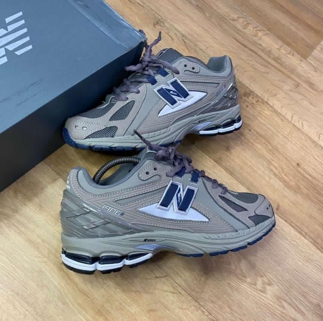 A pair of grey and blue New Balance 990R running shoes with box on wooden floor