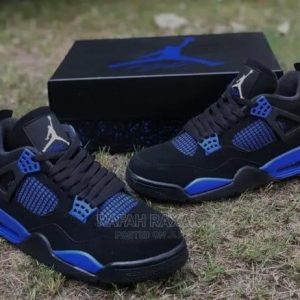 A pair of black and blue Air Jordan sneakers on a grassy field with the shoe box in the background, showcasing the sleek design and vibrant colors.