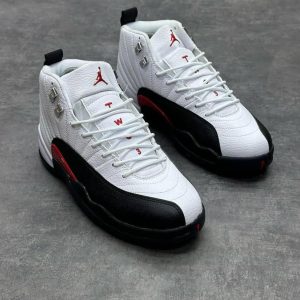 A pair of white, black, and red Air Jordan 12 Retro basketball shoes, showcasing the iconic Jumpman logo and sleek design.