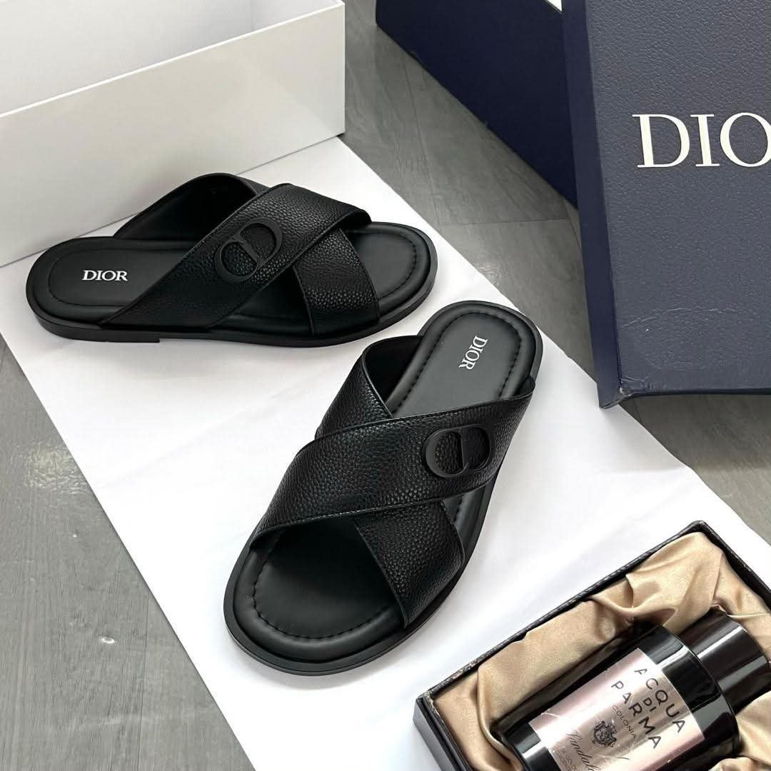 A pair of black leather Dior sandals on a white background, showcasing the sleek design and comfort features.