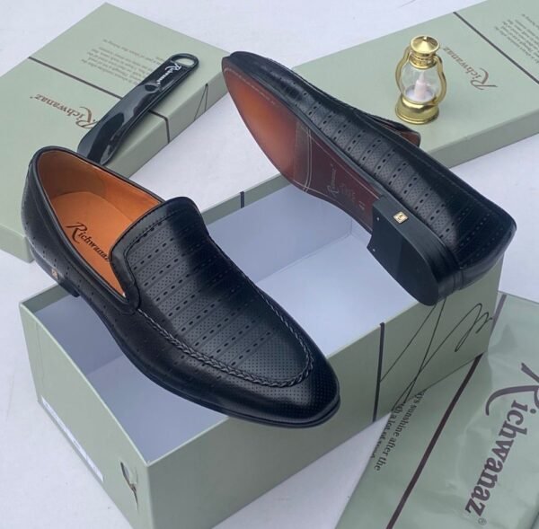 A pair of white leather loafers with perforations, displayed on a shoe box with a luxurious background, showcasing the shoe's intricate details and craftsmanship.
