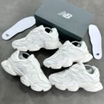 Luxurious all-white New Balance sneakers with sleek design and premium materials, presented with box and insoles.