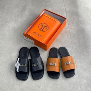 Luxury leather slides from Hermes, displayed in black and brown colors, with an orange box and bag in the background.