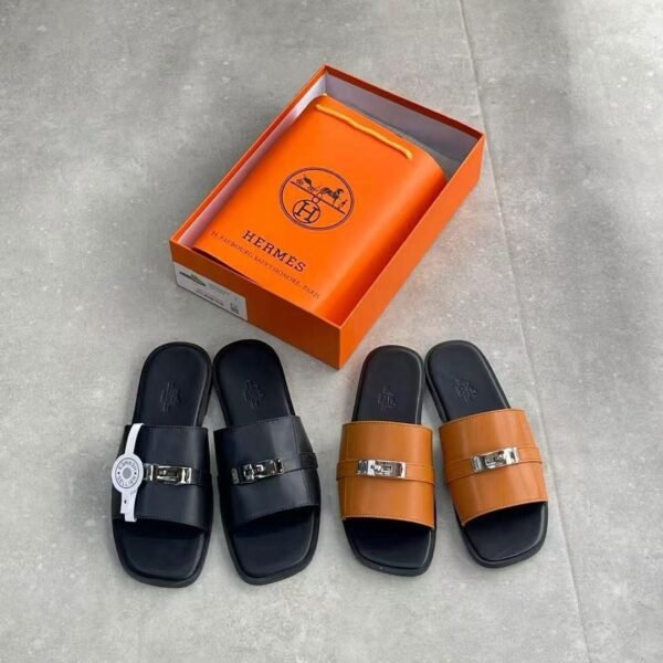 Luxury leather slides from Hermes, displayed in black and brown colors, with an orange box and bag in the background.