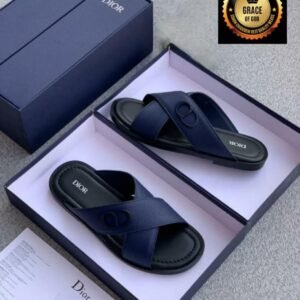 A pair of navy blue Dior slide sandals in an open box, showcasing the shoe's sleek design and comfort features, perfect for stylish and comfortable footwear.