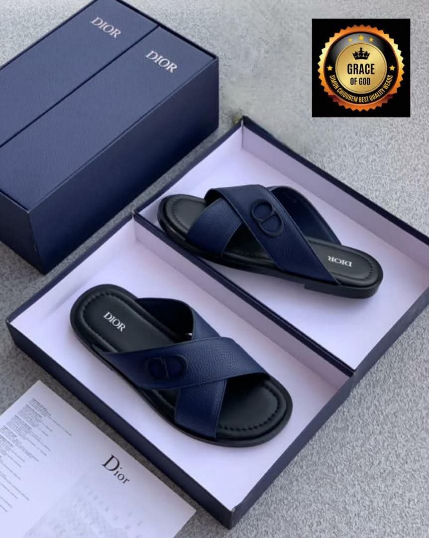 A pair of navy blue Dior slide sandals in an open box, showcasing the shoe's sleek design and comfort features, perfect for stylish and comfortable footwear.