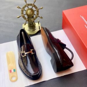 A pair of luxury men's loafers with gold buckle and red box on a white background, perfect for formal occasions.