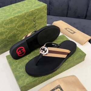 A pair of black Gucci sandals with interlocking GG logo on a green box and cloth bag, showcasing luxurious design and premium packaging.