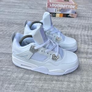 A pair of white leather kids' sneakers with diamond accents, placed on a wooden surface with luxury brand boxes in the background, exuding high-end fashion and style.