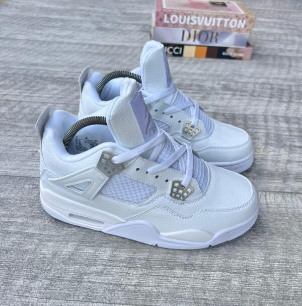 A pair of white leather kids' sneakers with diamond accents, placed on a wooden surface with luxury brand boxes in the background, exuding high-end fashion and style.