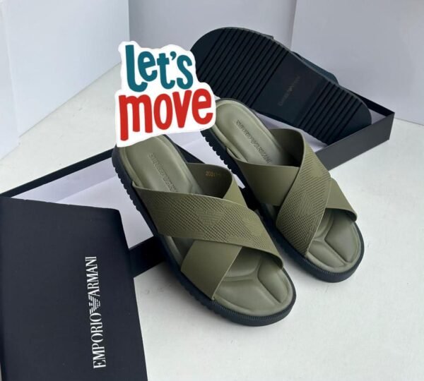 A pair of beige and black Emporio Armani inspired double strap slides on a beige surface with Emporio Armani boxes in the background.