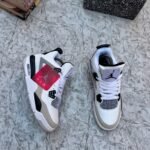 A pair of luxurious white and grey Air Jordan 4 sneakers on a marble surface, exuding high-end style and sophistication.