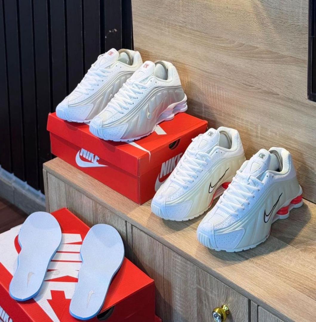 A pair of white Nike sneakers with red accents and matching slippers on a wooden shelf, perfect for adding a touch of style and comfort to your shoe collection.