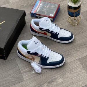 A pair of white, navy, and gold Nike Air Jordan 1 sneakers on a wooden floor, with a shoe box and game in the background.