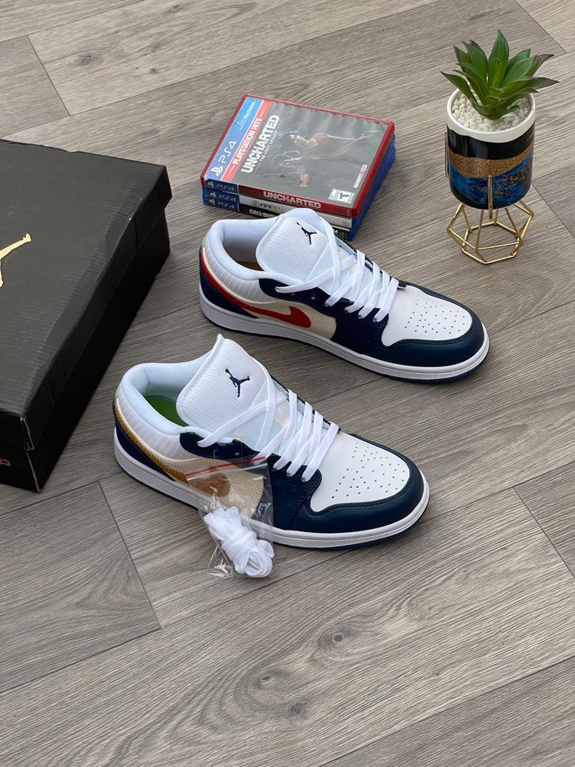A pair of white, navy, and gold Nike Air Jordan 1 sneakers on a wooden floor, with a shoe box and game in the background.