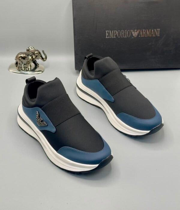 A pair of black and blue Emporio Armani sneakers with a white sole, displayed with a black box and a silver elephant figurine.