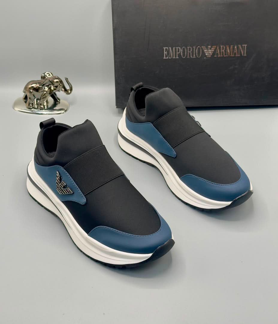 A pair of black and blue Emporio Armani sneakers with a white sole, displayed with a black box and a silver elephant figurine.