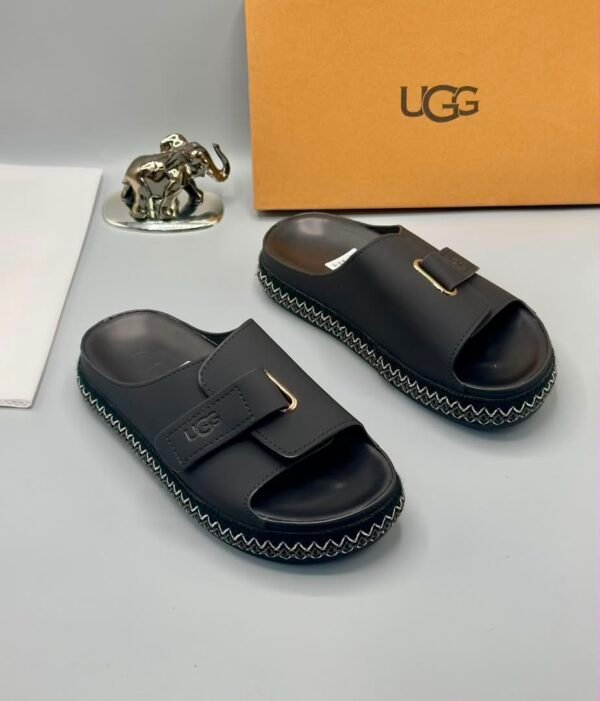 Grey UGG slide sandals with gold buckle and stitched sole, perfect for comfortable and stylish wear.