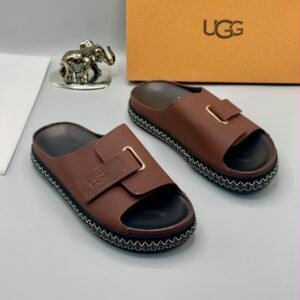 Grey UGG slide sandals with gold buckle and stitched sole, perfect for comfortable and stylish wear.