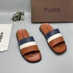 A pair of stylish brown slides with navy blue and white stripes, accompanied by a brown shoe box and accessories, all bearing the 'Pedro' brand name.