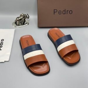 A pair of stylish brown slides with navy blue and white stripes, accompanied by a brown shoe box and accessories, all bearing the 'Pedro' brand name.