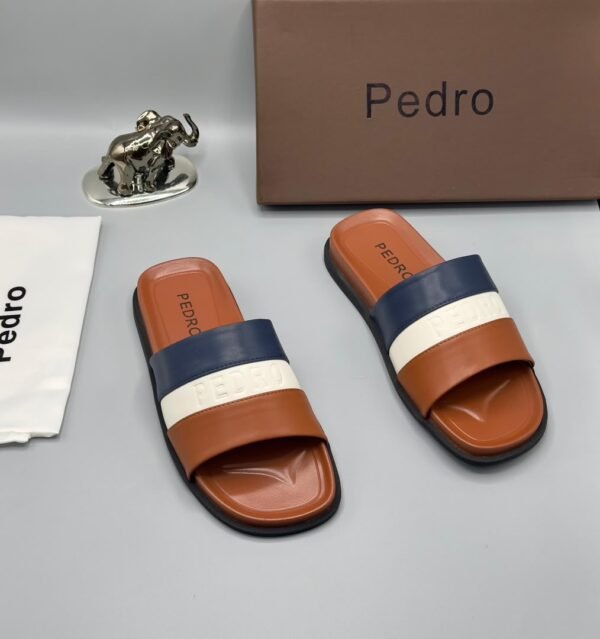 root A pair of stylish brown slides with navy blue and white stripes, accompanied by a brown shoe box and accessories, all bearing the 'Pedro' brand name.
